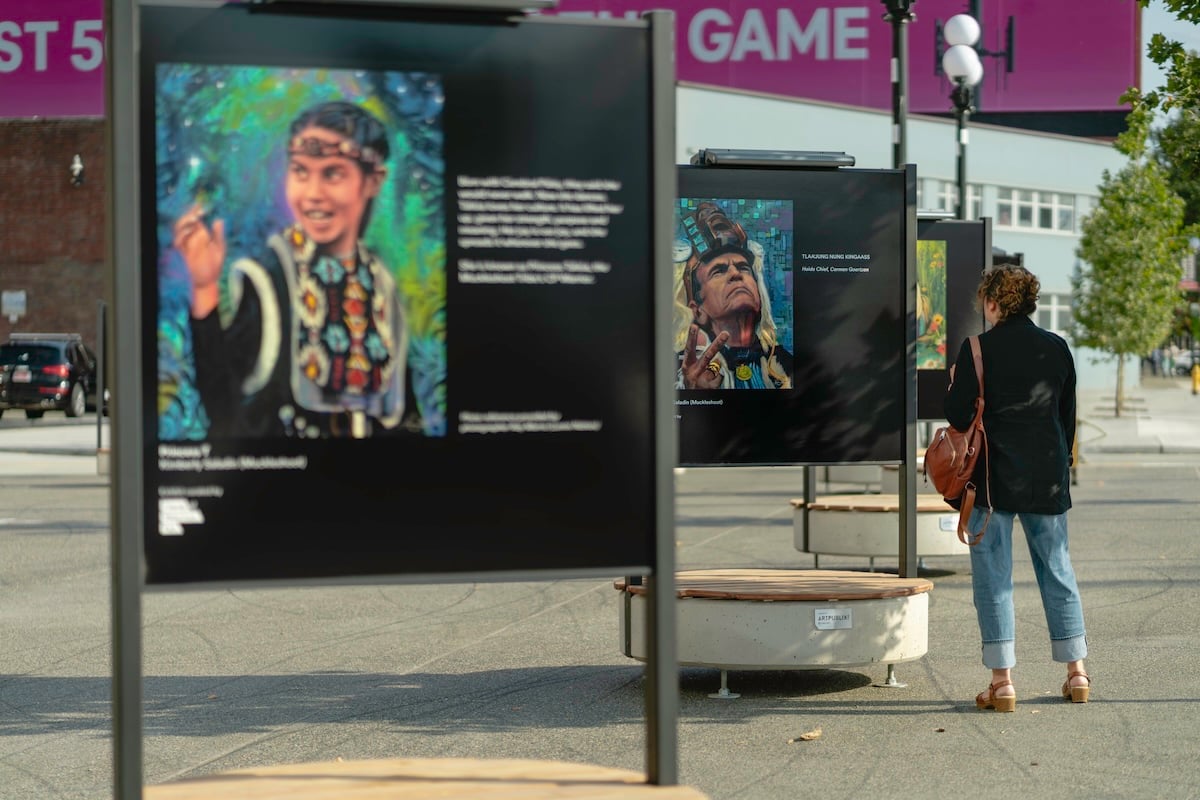 A person stands and views the outdoor art exhibit by artist Kimberly Saladin (Muckelshoot) at Stadium Plaza.